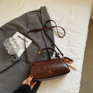 Detail view of a vintage dark coffee handbag with wood bead charm on a grey fabric base