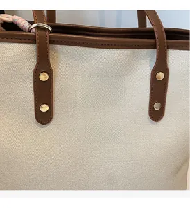 Close-up of contrast tote bag with beige woven fabric and brown leather detailing