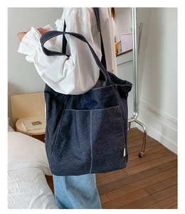 Détail du sac cabas en denim bleu foncé avec coutures blanches contrastées et grande poche