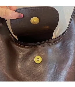 Detail of the golden magnetic buckle and zipper on the dark brown leather hobo bag