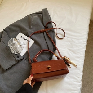 Close-up of a retro reddish-brown leather handbag with a vintage bronze twist lock