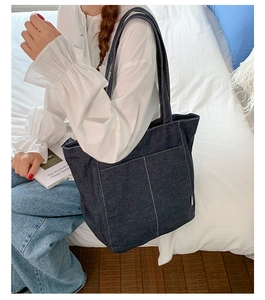Détail du sac cabas en denim bleu foncé avec surpiqûres blanches et poche frontale