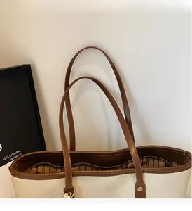 Detail of canvas tote bag with brown leather trim, zipper closure and striped inner lining