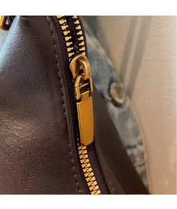 Detail of premium dark brown leather texture with smooth gold metal zipper and slider