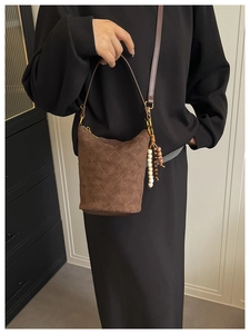 Détail du sac seau en daim marron foncé avec coutures matelassées et perles en bois