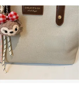 Detailed close-up of woven tote bag fabric with leather trim and ShellieMay plush charm