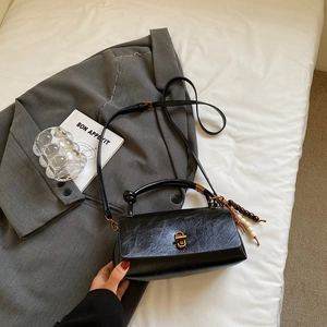 Detail of black vintage handbag with gold clasp, knotted handle and wooden bead charm