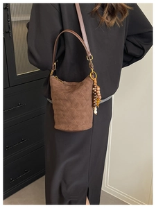 Détail du sac seau en daim marron avec matelassage en losanges et breloque en perles colorées