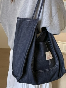 Deep blue denim tote bag with white contrast stitching and front pocket for school use