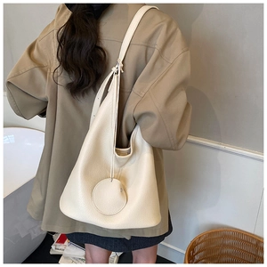Detail view of a beige pebbled leather hobo bag worn by a model for daily commute
