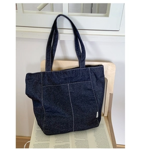 Gros plan du sac cabas en denim bleu foncé avec coutures contrastées blanches et poche