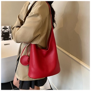 Close-up of a red leather hobo shoulder bag with litchi grain texture and leather charm