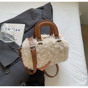 Detail of faux shearling texture and brown leather strap on the cream Boston handbag