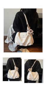 Detail showing the creamy white tote bag texture with lion plush pendant charm and fold design