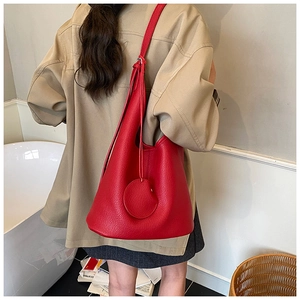 Side view of a large red pebbled leather bucket bag styled on a female model