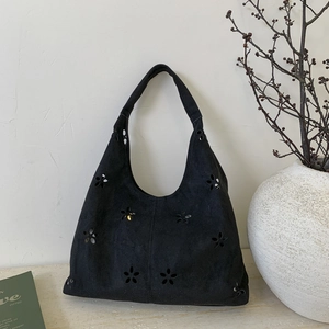 Detail shot of black faux suede tote bag with floral laser-cut hollow design patterns