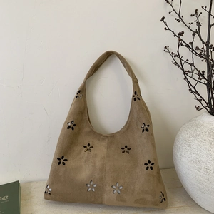 Detailed view of camel faux suede tote bag with laser-cut floral patterns and texture