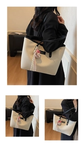 Detail view of large canvas tote bag with black leather trim and cute plush pendant