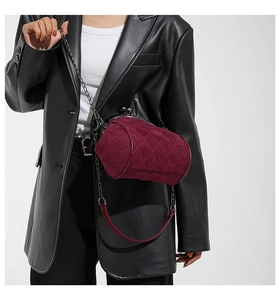 Macro detail of wine red quilted cylinder bag with vintage metal clasp and chain strap