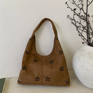 Detailed macro view of laser-cut floral pattern on brown suede leather tote bag