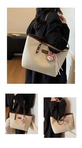 Detail of canvas tote bag featuring premium leather trim and a cute plush bear charm