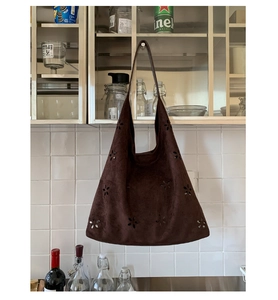 Close-up of dark brown faux suede tote bag with intricate floral hollow-out pattern detail