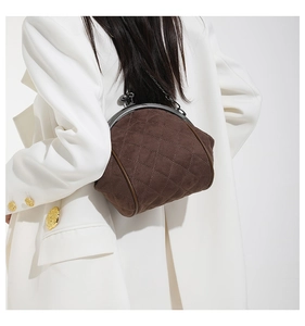 Brown quilted shell bag with gold clasp shown on model wearing white suit