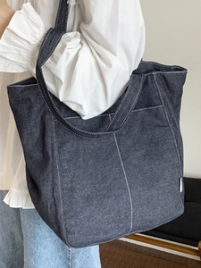 Grand sac cabas en jean bleu foncé avec surpiqûres blanches porté par un mannequin
