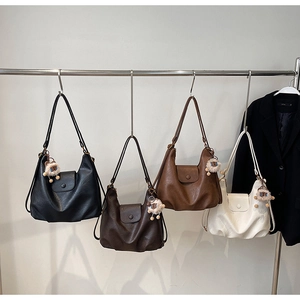 Detail of four chic Hobo shoulder bags in black, brown, and cream with cute bear charms