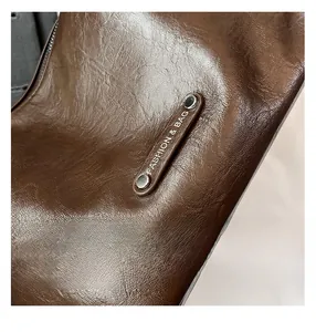 Close-up of brown pebbled leather texture with silver rivet and Fashion & Bag logo