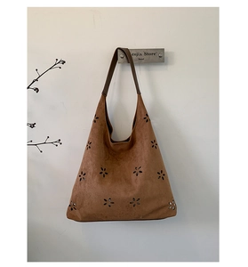 Detail of laser-cut floral pattern on vintage brown suede tote bag with reinforced handles