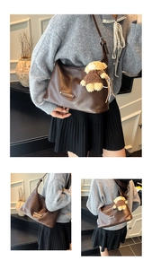 Detail view of a vintage dark brown tote bag with bear charm and adjustable strap
