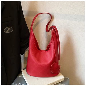 Close-up of red lychee grain leather bucket bag with adjustable strap and circular charm
