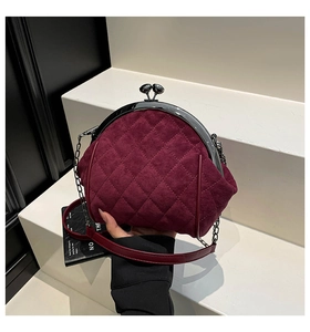Detail of burgundy quilted suede bag with vintage metal clasp and elegant chain strap