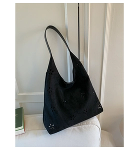 Detailed laser-cut floral pattern on a black suede hobo shoulder bag for women