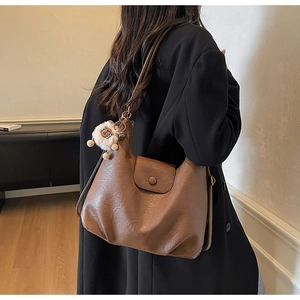 Detail view of brown hobo shoulder bag with a cute white alpaca plush charm accessory