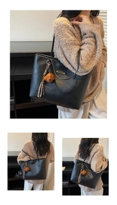 Detail of black faux leather tote bag featuring a cute brown bear charm and tassel
