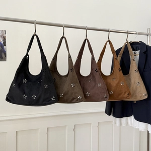 Close-up of suede tote bags with laser-cut floral patterns in various earth tones