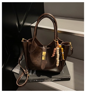 Detalle del bolso tipo cubo en cuero marrón con borde ondulado y cuentas de madera