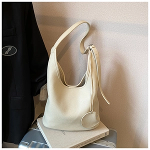Detail view of cream bucket bag with lychee texture and round coin purse charm