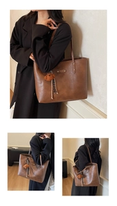 Detailed view of brown leather tote bag featuring metal logo plate and plush bear charm