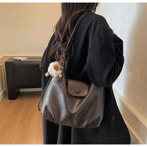Detail of dark brown vintage Hobo bag with plush charm and faux leather texture