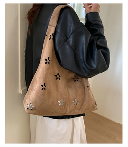 Detail view of camel suede tote bag showing intricate laser-cut hollow floral patterns