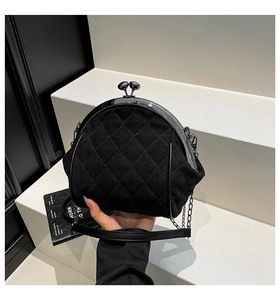 Close-up of black quilted velvet doctor bag with vintage metal clasp and leather chain strap