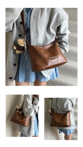 Detail of a brown faux leather tote bag with a small bear pendant on a grey cardigan