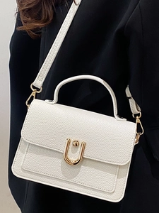 White lychee pattern shoulder bag with a gold U-shaped buckle on a black blazer background