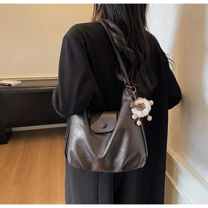 Deep brown vintage leather hobo bag with plush pendant shown in shoulder wear detail