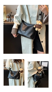Detail of black leather tote bag featuring a cute teddy bear charm and metal fashion label