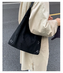 Detailed close-up of laser-cut floral patterns on a black matte shoulder tote bag