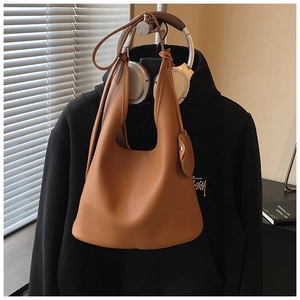 Brown litchi leather bucket bag detail with round charm and textured finish